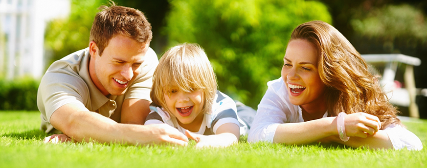 Family laying on grass and smiling