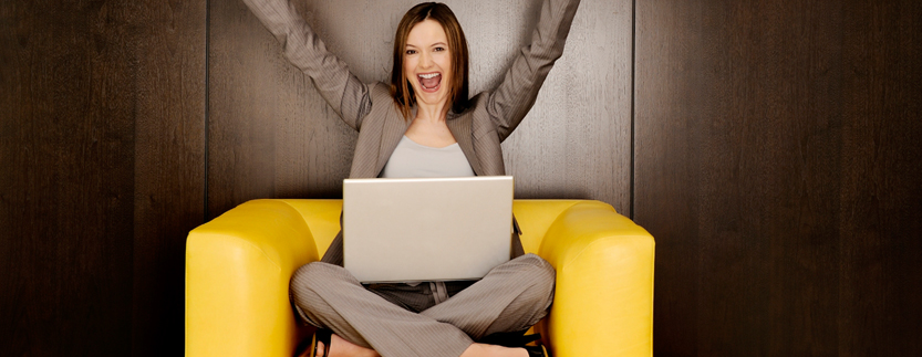 Woman with Computer Raising Hands and Smiling