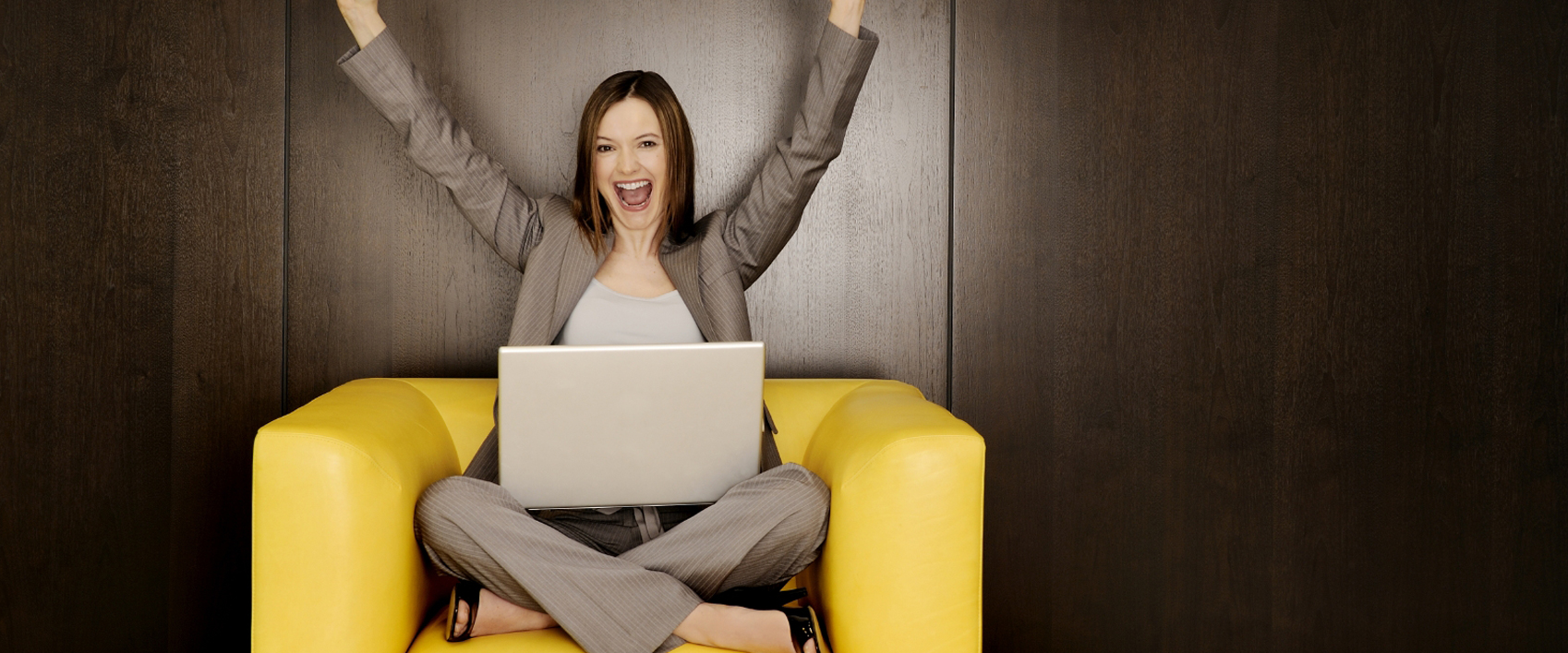 Woman with Computer Raising Hands and Smiling